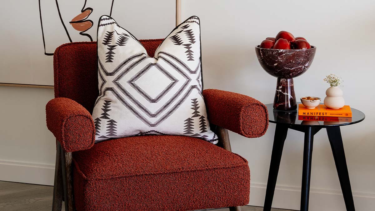 Armchair with patterned pillow and side table with decor